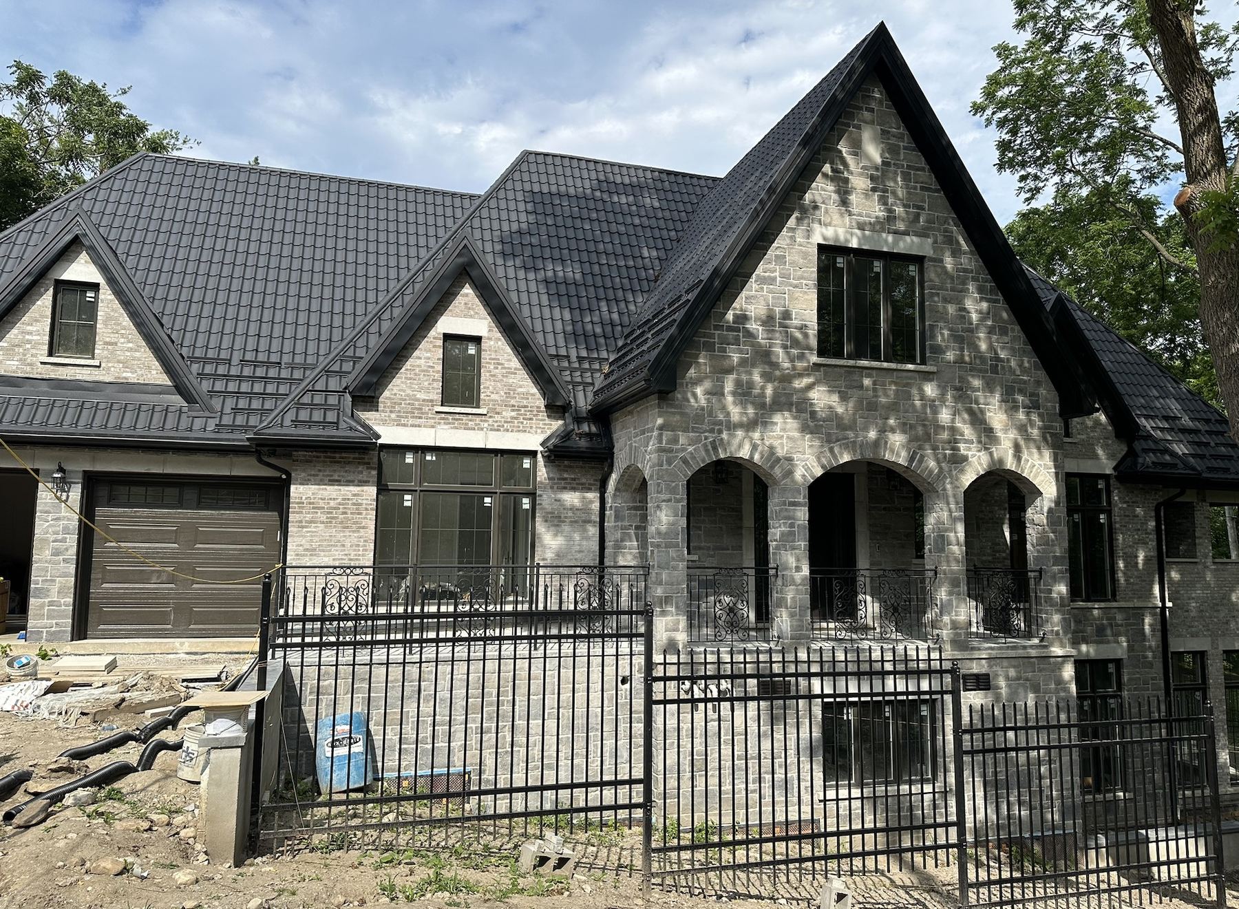 Custom stone and brick home built by Cavacor LTD with arched stone entrance and black metal roof