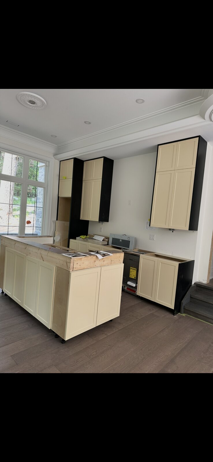 Custom kitchen island and cabinetry nearing completion in a cream and black finish