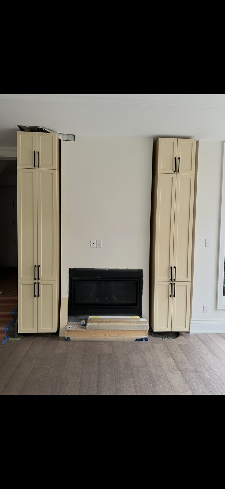 Custom built-in media cabinetry towers flanking a fireplace nook