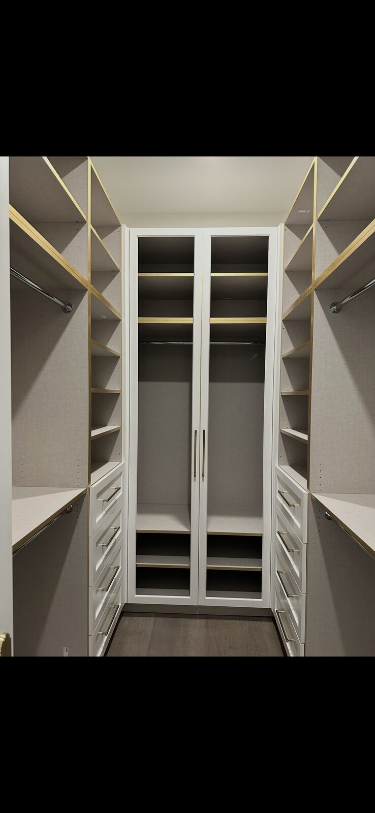 Custom walk-in closet system with open shelving and brass accents