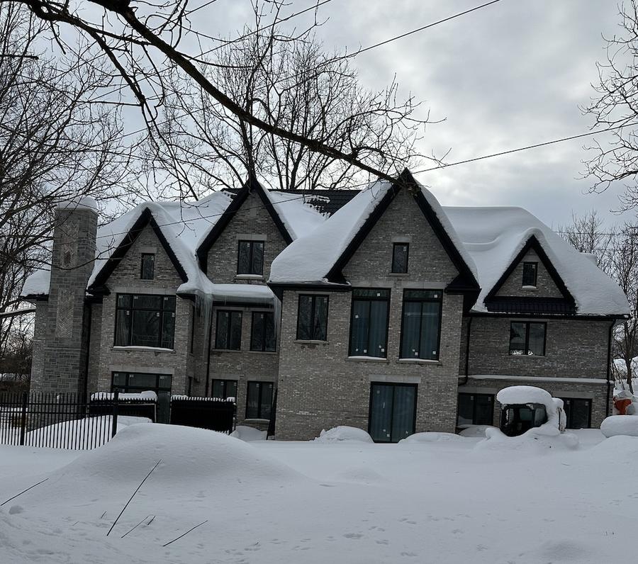 Completed brick custom home with stone chimney, photographed in winter