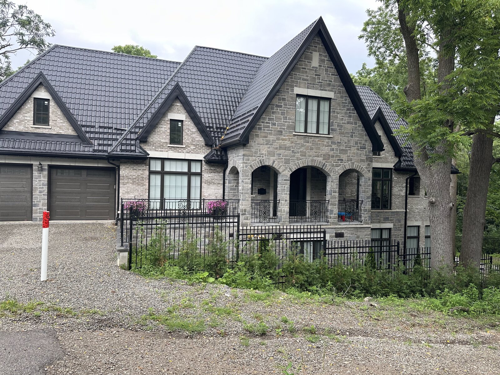 Completed custom home exterior with finished landscaping, fencing, and plantings